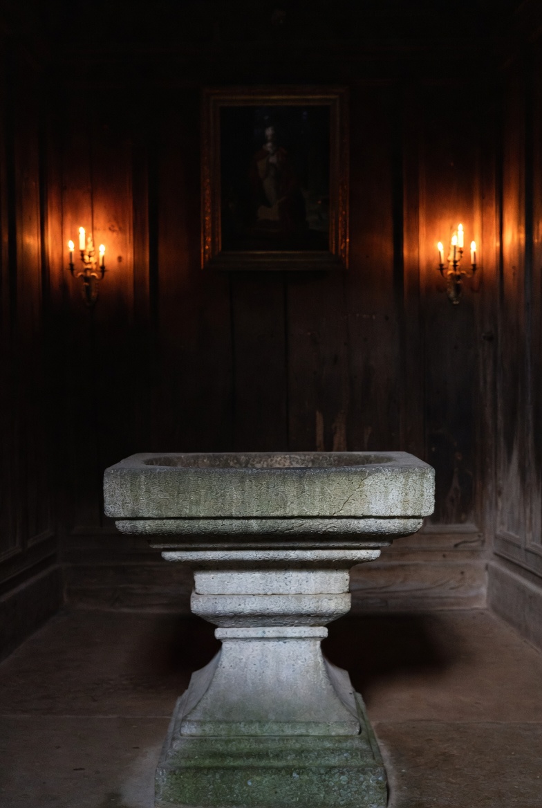 A dim stone shrine, candlelit, with an empty altar basin.
